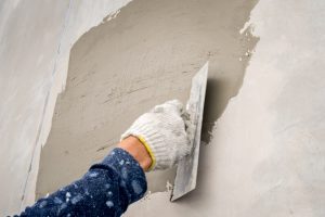 Hand applying cement on wall made with ready mix concrete.