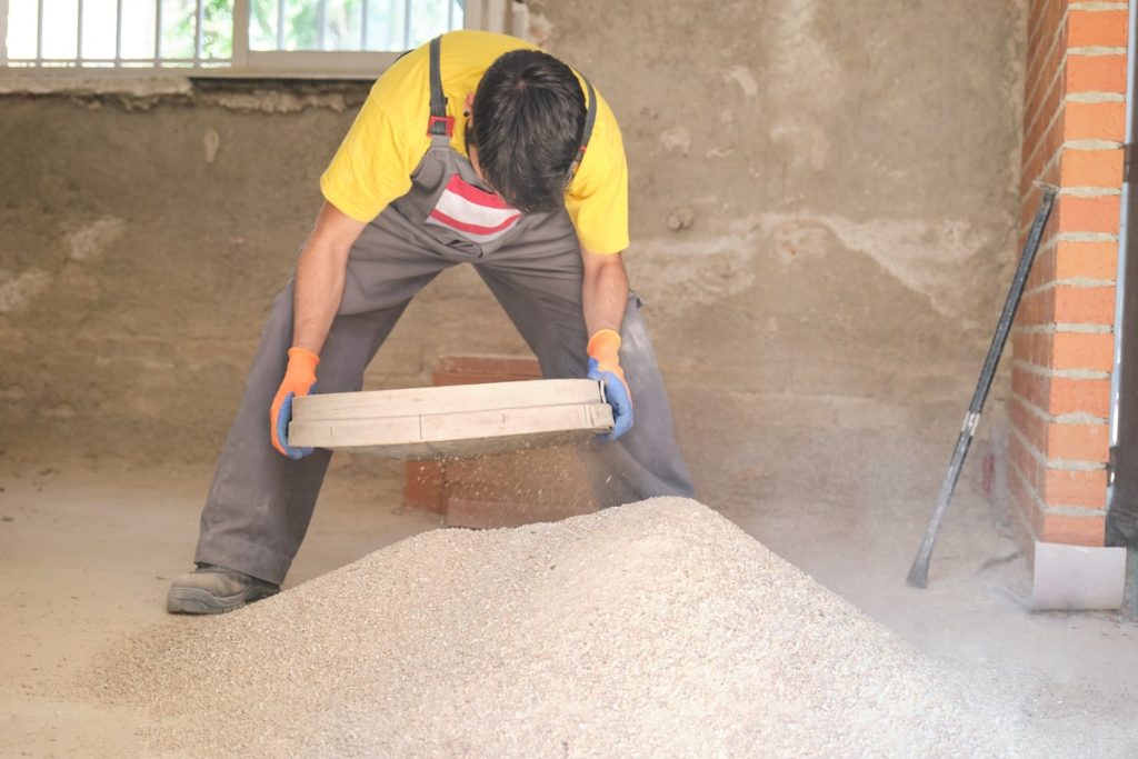 a young builder sieving through masonry sand