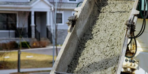 Close-up Of A Construction Chute Pouring Stucco In Front Of A Residential Building