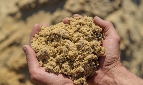 A person holding mason's sand in both hands, emphasizing its fine, smooth texture ideal for masonry and construction.